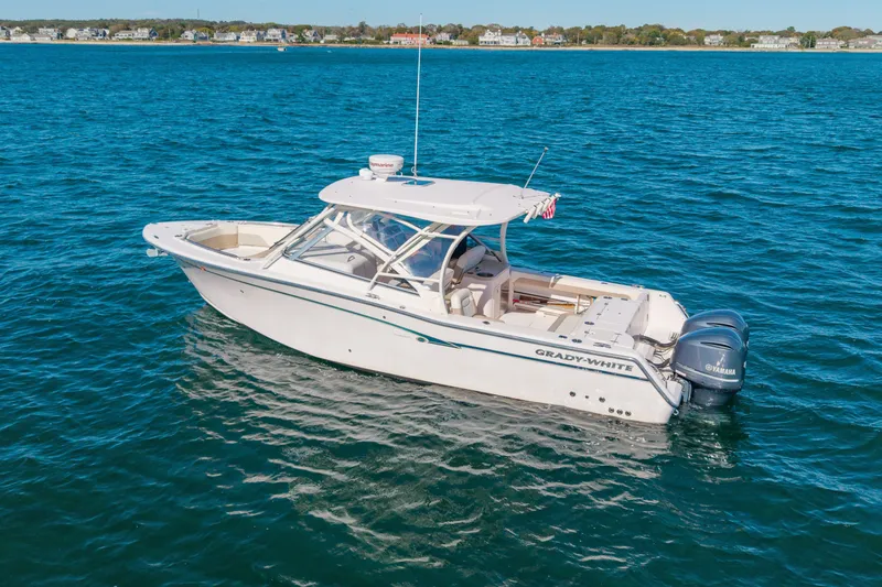 Slide: The Image of 2014 Grady-White Freedom 307 boat on blue ocean water, near coastal homes. - 47