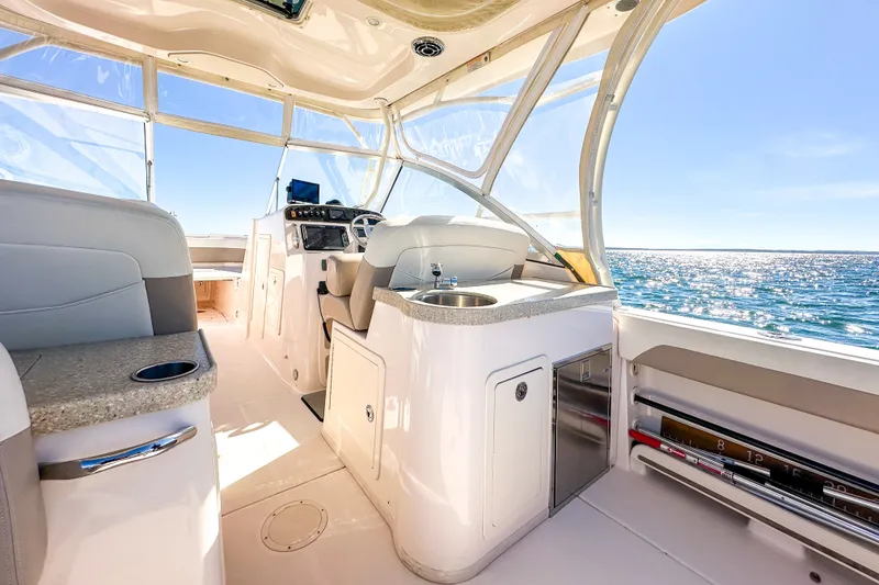 Slide: The Image of 2014 Grady-White Freedom 307 boat interior with ocean view, featuring helm and seating area. - 26