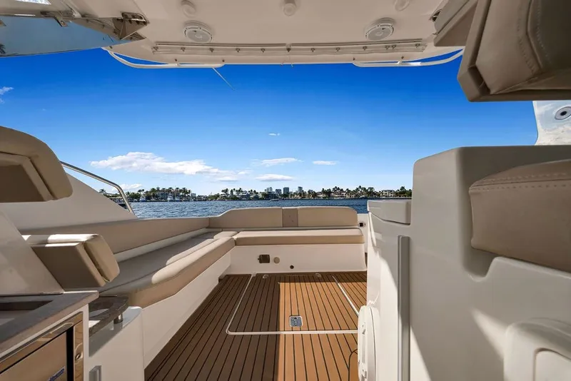 Slide: The Image of 2017 Pursuit SC 365i Sport Coupe interior with waterfront view, featuring sleek seating and wood flooring. - 18
