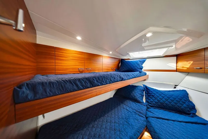 Slide: The Image of 2017 Pursuit SC 365i Sport Coupe cabin with blue bedding and wooden accents. - 36
