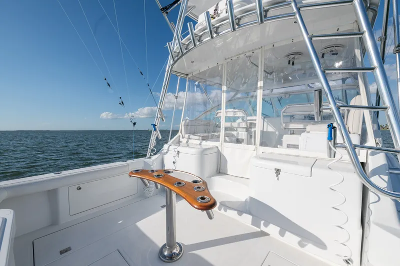 Slide: The Image of 2005 Cabo 35 Express yacht deck with fishing rod holders and ocean view. - 12