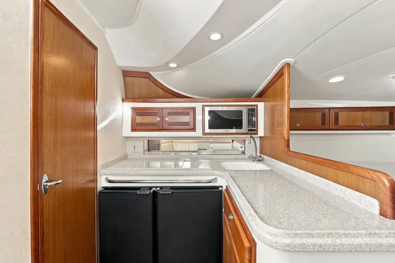 Slide: The Image of 2005 Cabo 35 Express yacht interior kitchen with wood cabinetry and modern appliances. - 22