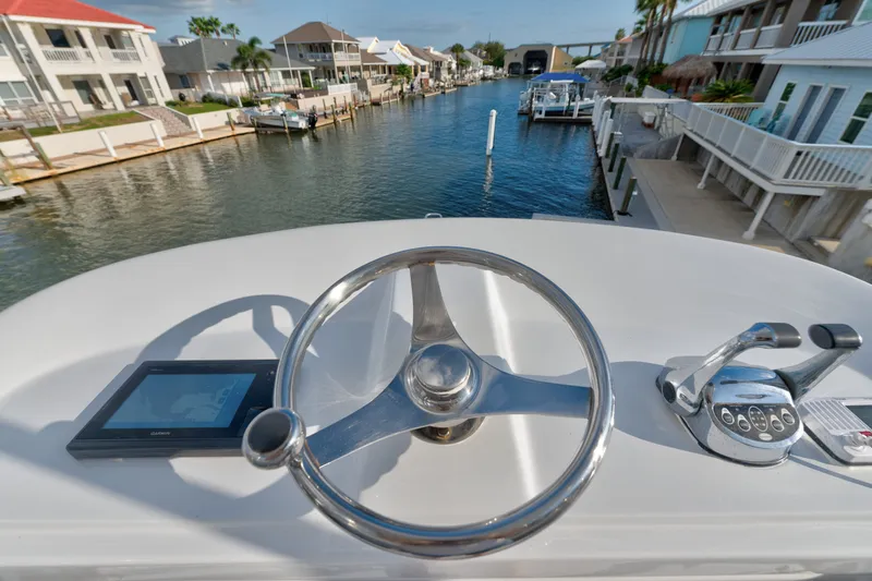Slide: The Image of Helm view of 2005 Cabo 35 Express boat navigating a residential canal. - 14