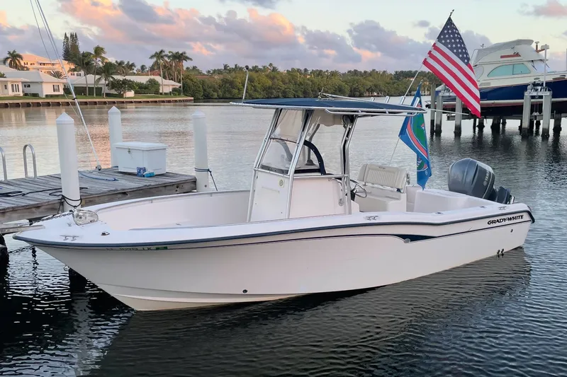 The Image of 2001 Grady-White Advance 247 boat docked, featuring American flag, calm waters, and scenic background. - 0
