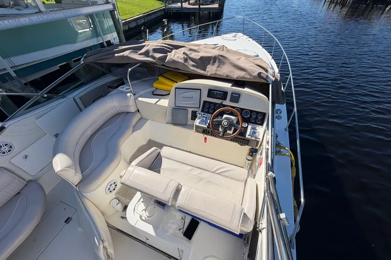 Slide: The Image of 2000 CUISERS Cruisers 3575 Express boat cockpit with steering wheel and seating, docked by water. - 4