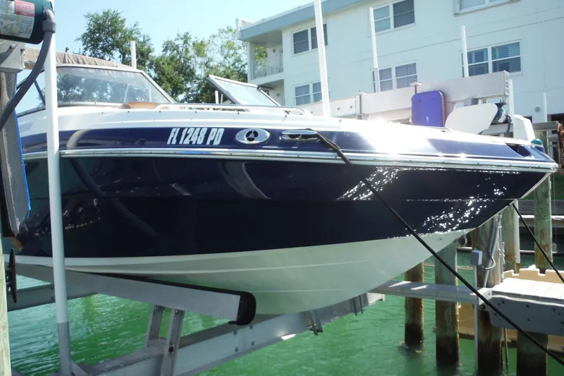 Slide: The Image of 2011 Yamaha Boats 242 Limited on lift, docked near waterfront building. - 48