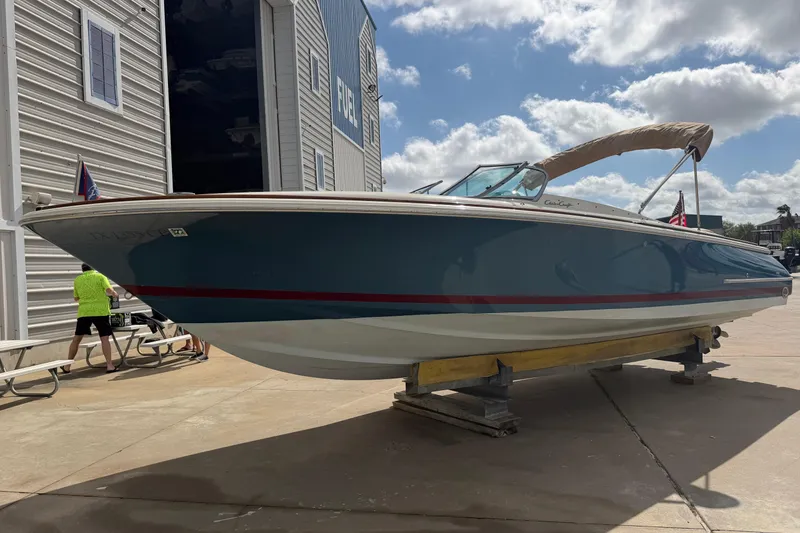 Slide: The Image of 2001 Chris-Craft Launch 28 boat on display outside a storage facility under a cloudy sky. - 4