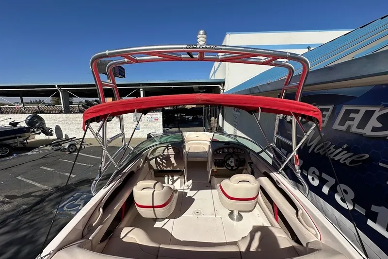 Slide: The Image of 2000 Chaparral 216 SSi boat with red canopy and seating, parked outdoors. - 9