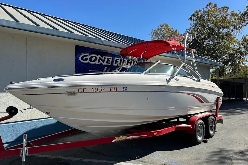 The Image of 2000 Chaparral 216 SSi boat with red canopy on trailer, parked outdoors. - 0