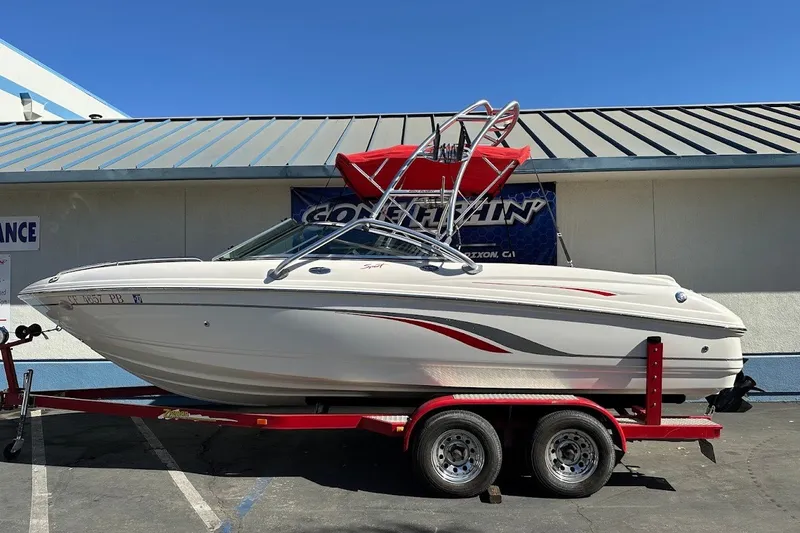 Slide: The Image of 2000 Chaparral 216 SSi boat on trailer, white with red accents, parked outdoors. - 1