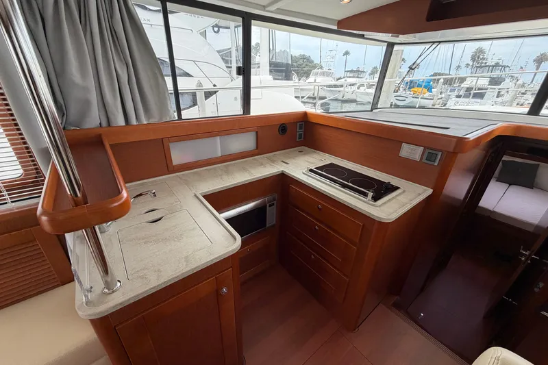 Slide: The Image of Interior of 2019 Beneteau Swift Trawler 44, featuring a compact kitchen with stove and sink. - 23