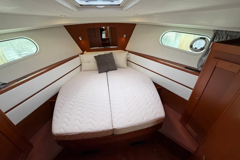 Slide: The Image of Cozy cabin interior of 2019 Beneteau Swift Trawler 44 with double bed and porthole windows. - 28
