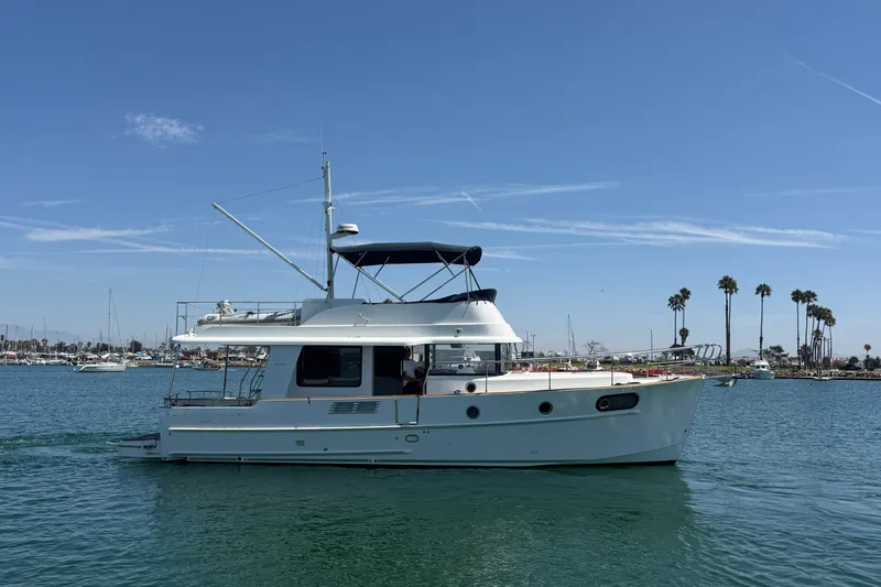 Slide: The Image of 2019 Beneteau Swift Trawler 44 cruising on a sunny day near palm-lined shore. - 1