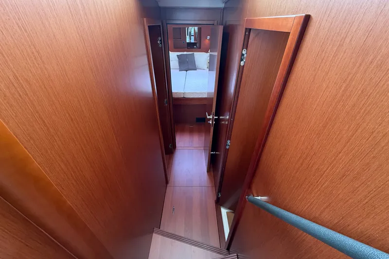 Slide: The Image of Interior hallway of 2019 Beneteau Swift Trawler 44, featuring wooden paneling and bedroom view. - 25