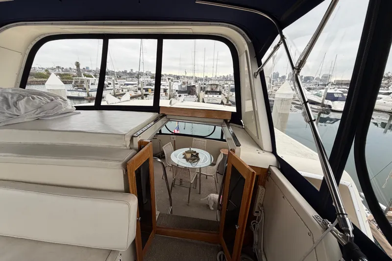 Slide: The Image of 1989 Californian Aft Cabin yacht interior with marina view, featuring seating and table. - 14