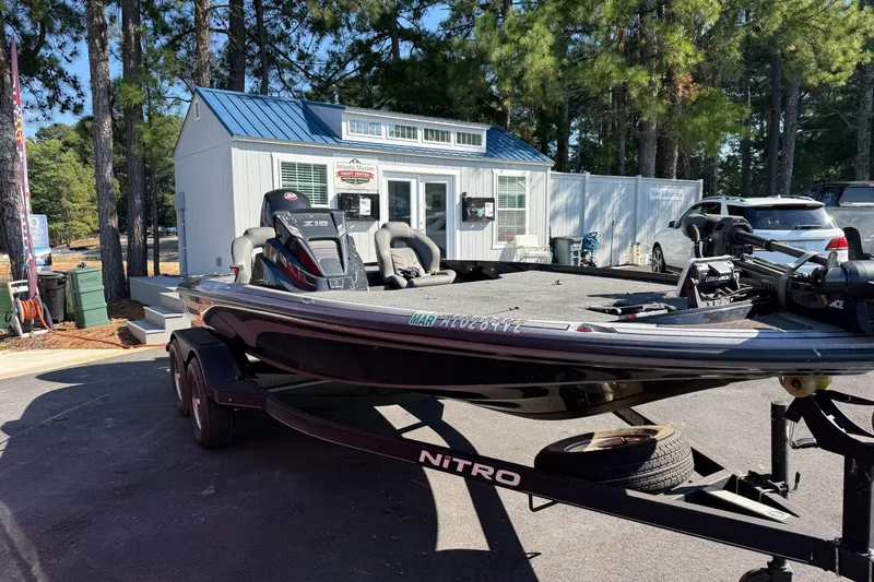 The Image of 2024 Nitro Z18 boat on trailer, parked near a marine shop with trees in the background. - 0