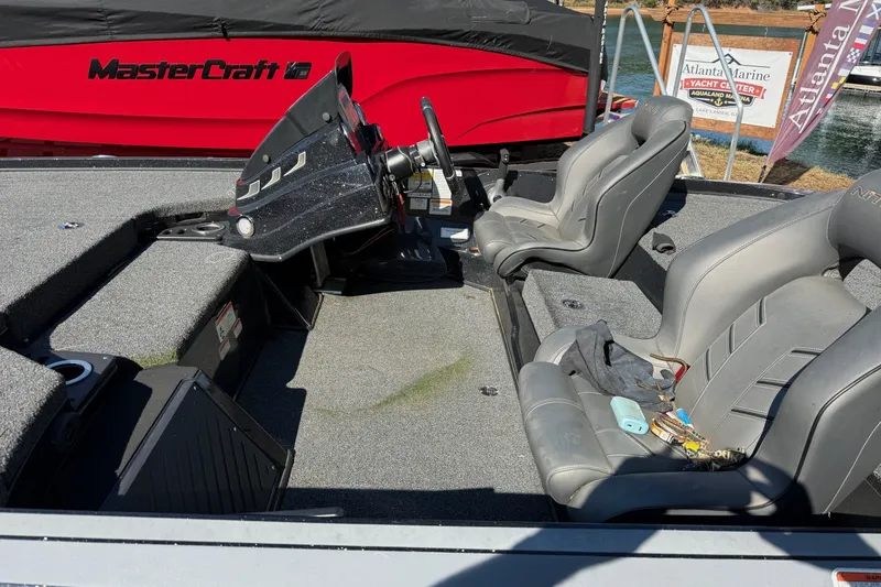 Slide: The Image of 2024 Nitro Z18 boat interior with gray seats and steering console, docked near water. - 6