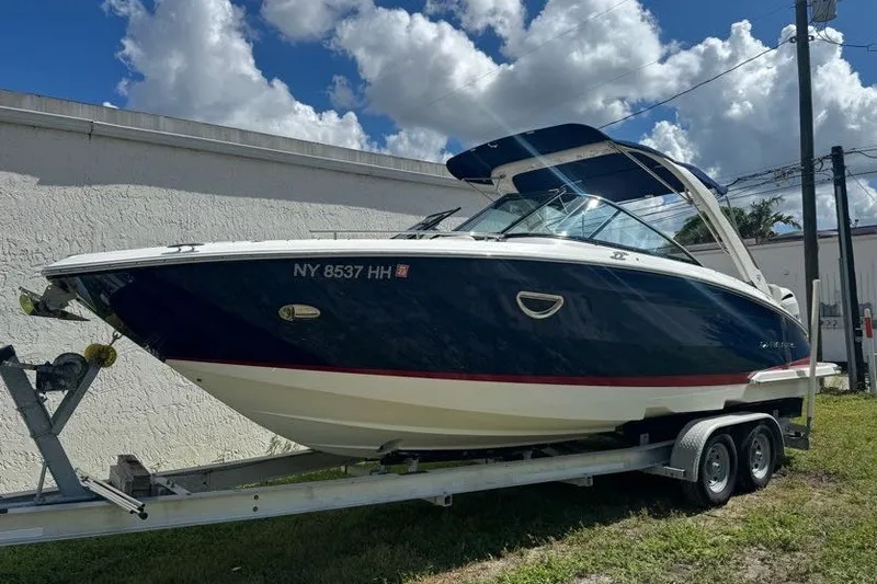 Slide: The Image of 2021 Regal 29 OBX boat on trailer, parked outdoors under a partly cloudy sky. - 1