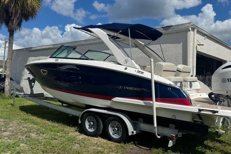 Slide: The Image of 2021 Regal 29 OBX boat on trailer, parked outdoors under a blue sky. - 2