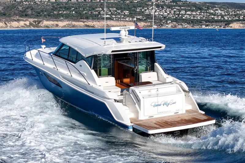 Slide: The Image of 2021 Tiara C 44 Coup yacht cruising on ocean near scenic coastline. - 60