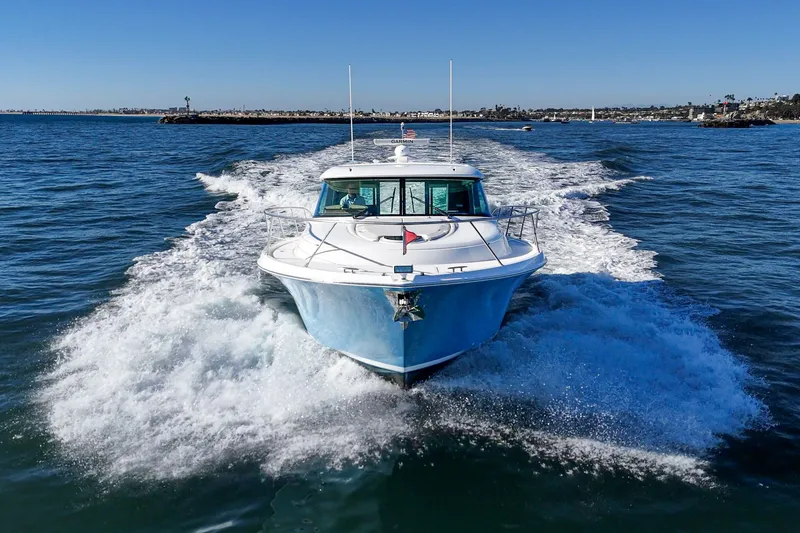 Slide: The Image of 2021 Tiara C 44 Coup yacht cruising on open water, creating a wake. - 68