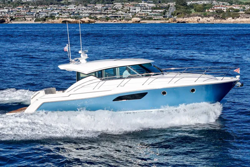 Slide: The Image of 2021 Tiara C 44 Coup yacht cruising on blue ocean near coastal town. - 54
