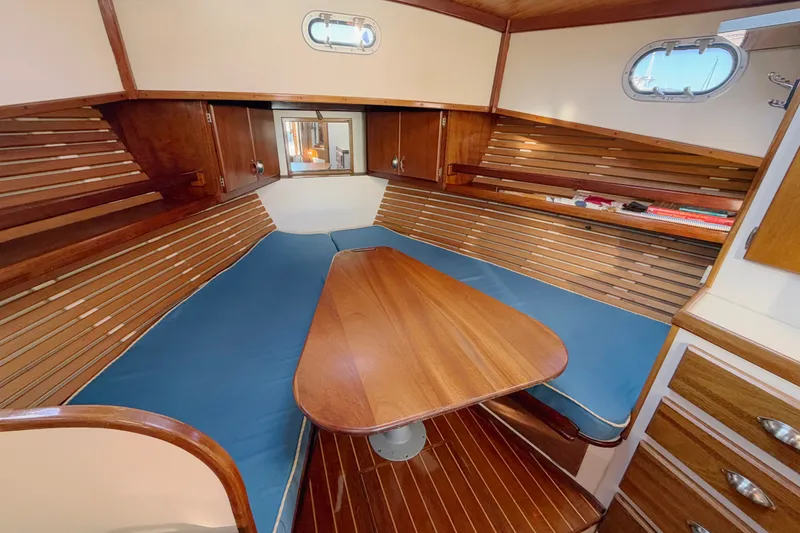 Slide: The Image of Cozy 1997 Covey Island Spencer Lincoln boat interior with wooden table and blue seating. - 13
