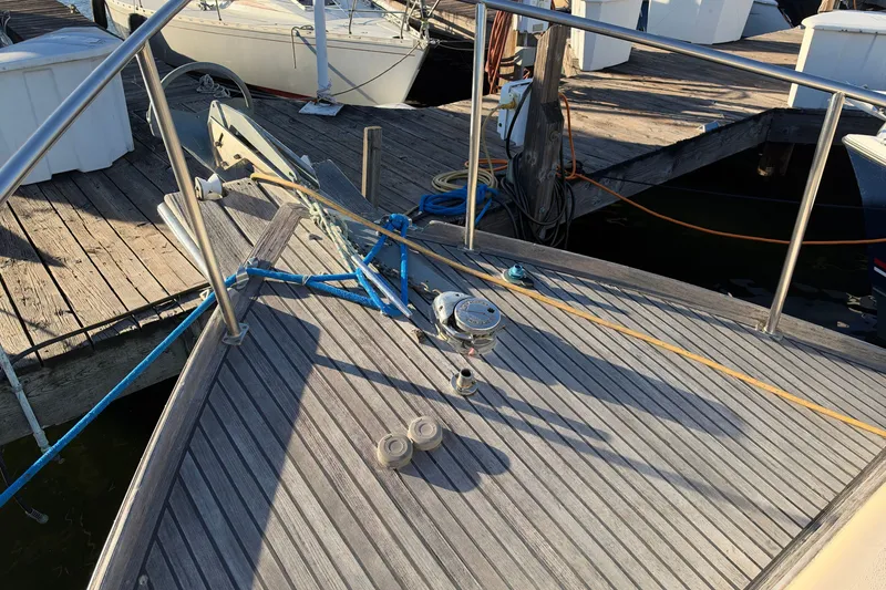 Slide: The Image of Bow of a 1997 Covey Island Spencer Lincoln boat docked, featuring wooden deck and anchor. - 27