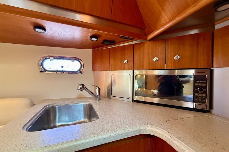 Slide: The Image of 2006 Tiara Yachts 3600 Sovran kitchen with sink, microwave, and wooden cabinetry. - 26