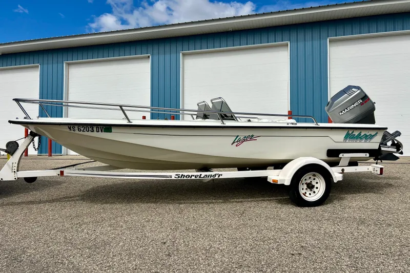 Slide: The Image of 1995 Wahoo 1650 boat on trailer, parked outside blue warehouse. - 29