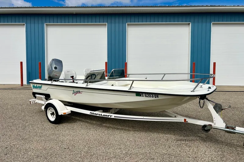 The Image of 1995 Wahoo 1650 boat on trailer, parked in front of blue garage doors. - 0