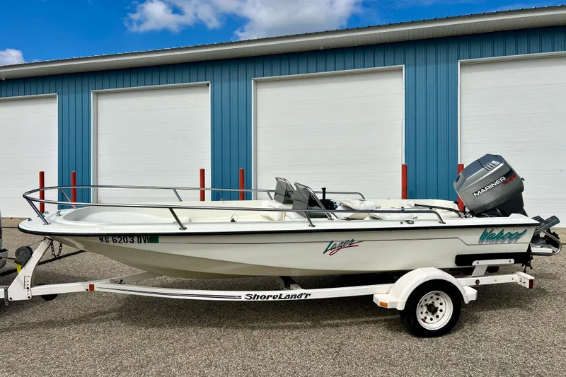Slide: The Image of 1995 Wahoo 1650 boat on trailer, parked outside blue storage facility. - 28