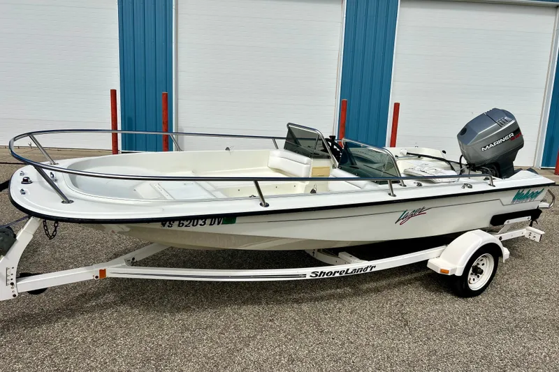 Slide: The Image of 1995 Wahoo 1650 boat on trailer with Mariner engine, parked near blue doors. - 30