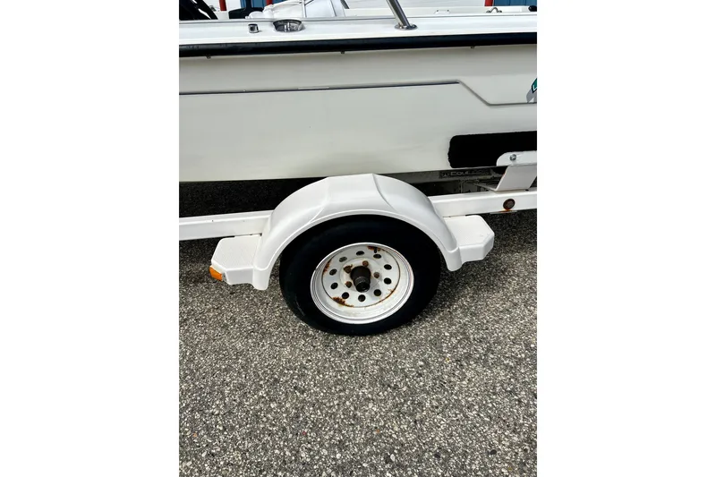 Slide: The Image of Trailer wheel of a 1995 Wahoo 1650 boat on asphalt surface. - 35