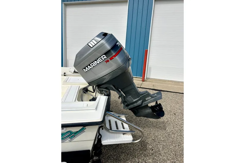 Slide: The Image of 1995 Wahoo 1650 boat with Mariner 75 outboard motor, parked near blue building. - 36
