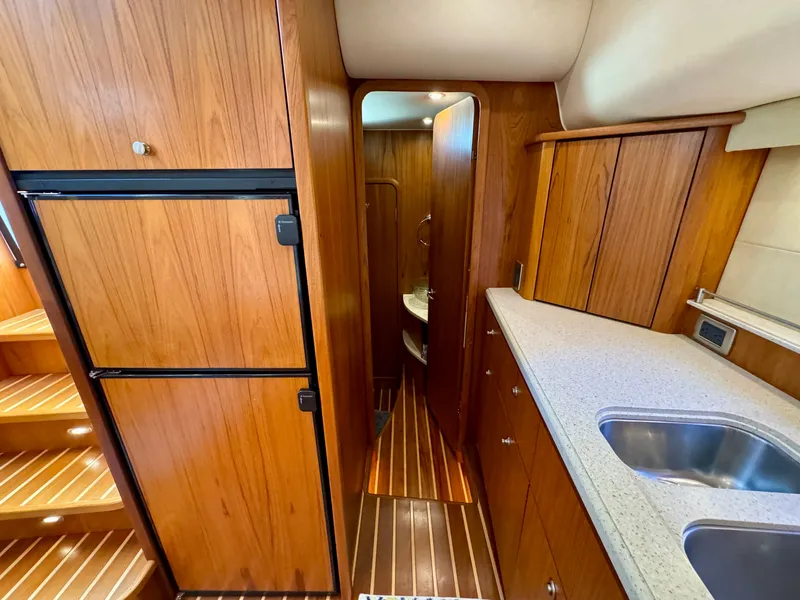 Slide: The Image of The interior of a 2006 Tiara Yachts 4300 Sovran features a well-equipped galley with wood paneling. - 44