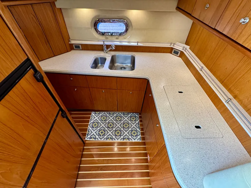 Slide: The Image of The 2006 Tiara Yachts 4300 Sovran galley features a sink, wooden cabinets, and a window. - 40