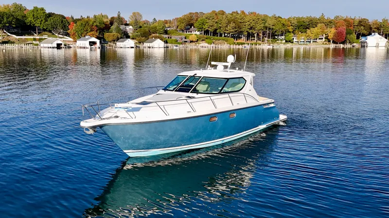 Slide: The Image of 2006 Tiara Yachts 4300 Sovran on calm water, surrounded by autumn trees and boathouses. - 14