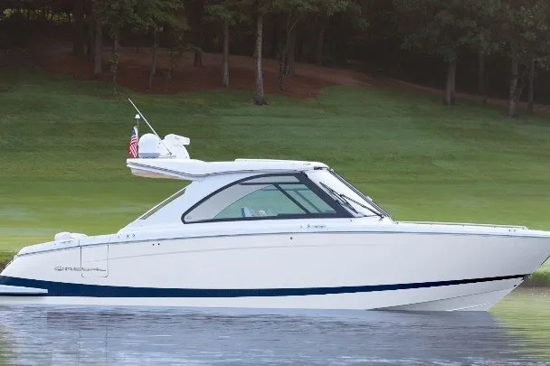 The Image of 2027 Regal LS36 boat on calm water with lush green background. - 0