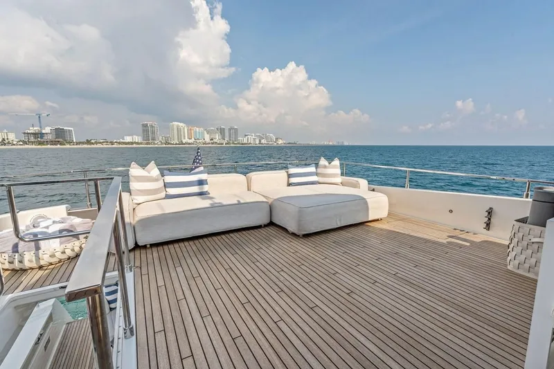 Slide: The Image of Luxurious 2022 Ferretti 850 yacht deck with plush seating, ocean view, and city skyline. - 16
