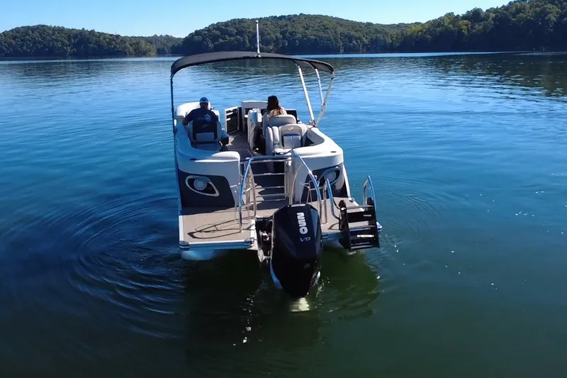 Slide: The Image of 2023 Barletta CORSA 23QSS pontoon boat cruising on a serene lake. - 2
