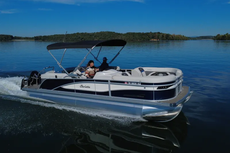 The Image of 2023 Barletta CORSA 23QSS pontoon boat cruising on a serene lake. - 0