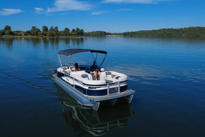 Slide: The Image of 2023 Barletta CORSA 23QSS pontoon boat cruising on a serene lake under a clear blue sky. - 3
