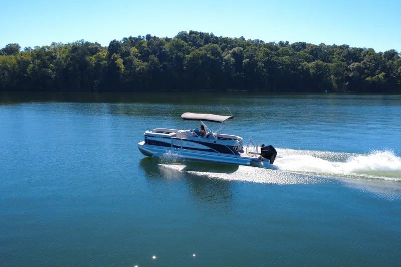 Slide: The Image of 2023 Barletta CORSA 23QSS pontoon boat cruising on a serene lake. - 5