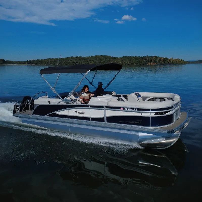 The Image of 2023 Barletta CORSA 23QSS pontoon boat cruising on a serene lake. - 0