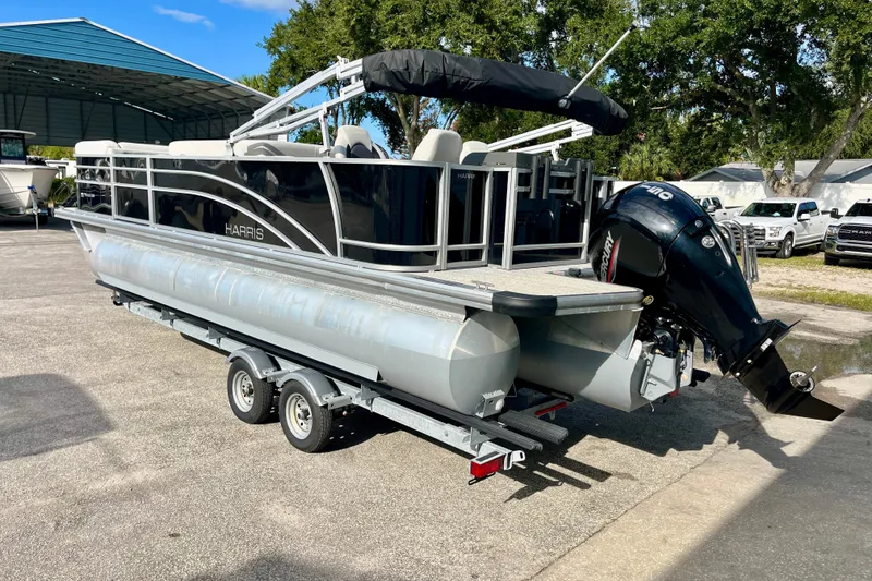 Slide: The Image of 2024 Harris Cruiser 230 pontoon boat on trailer, featuring sleek design and powerful outboard motor. - 19
