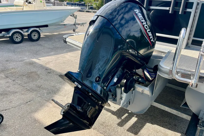 Slide: The Image of 2024 Harris Cruiser 230 with Mercury outboard motor, parked on a trailer. - 18