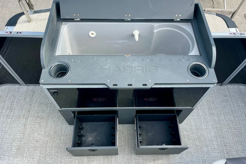 Slide: The Image of 2024 Harris Cruiser 230 boat console with sink, storage compartments, and cup holders. - 12