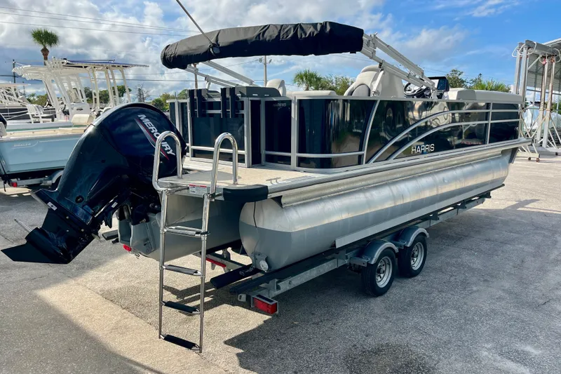 Slide: The Image of 2024 Harris Cruiser 230 pontoon boat on trailer with Mercury outboard motor. - 17