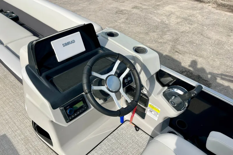 Slide: The Image of 2024 Harris Cruiser 230 boat helm with steering wheel and Simrad display. - 6